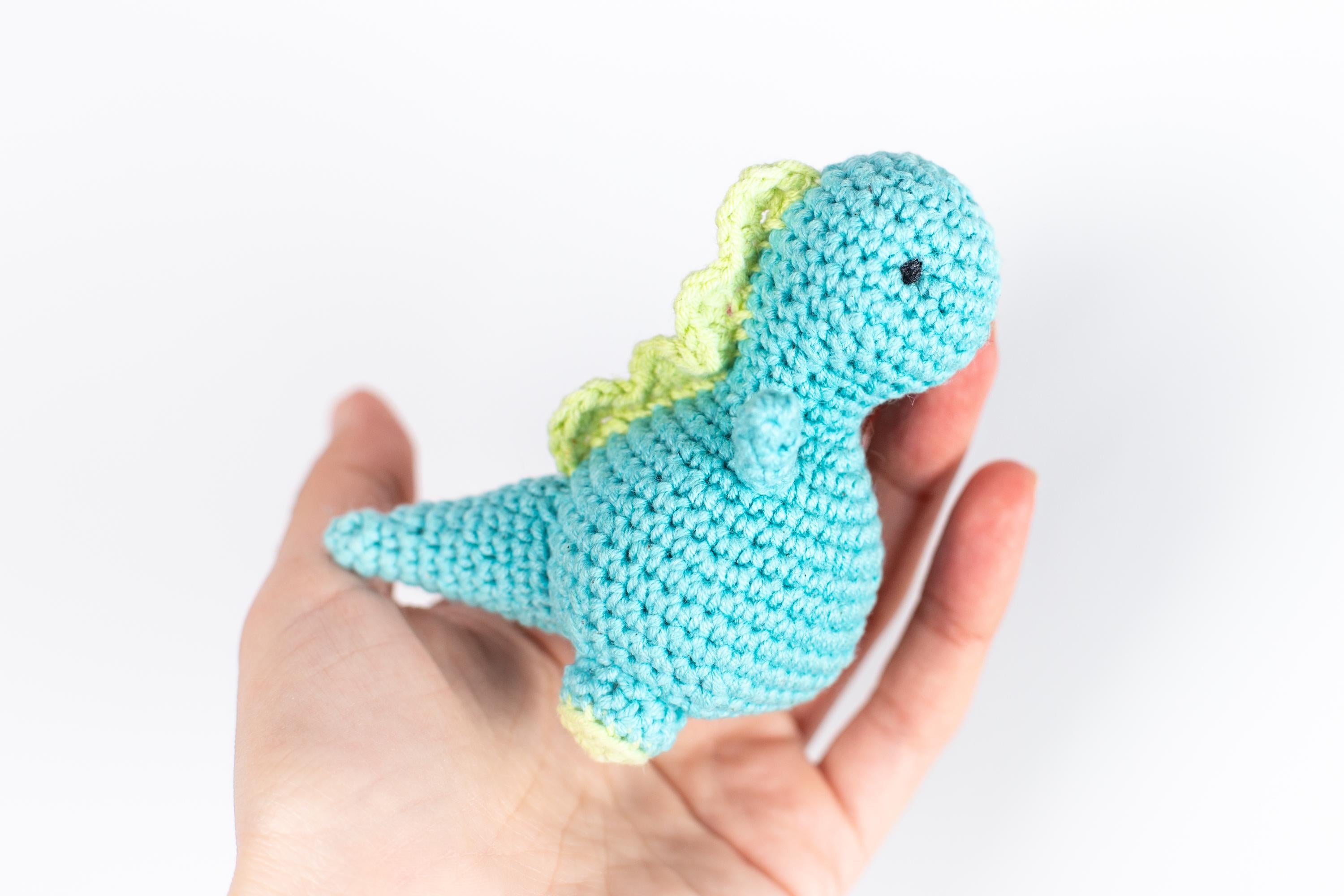 a hand holding a small crocheted toy in it's palm